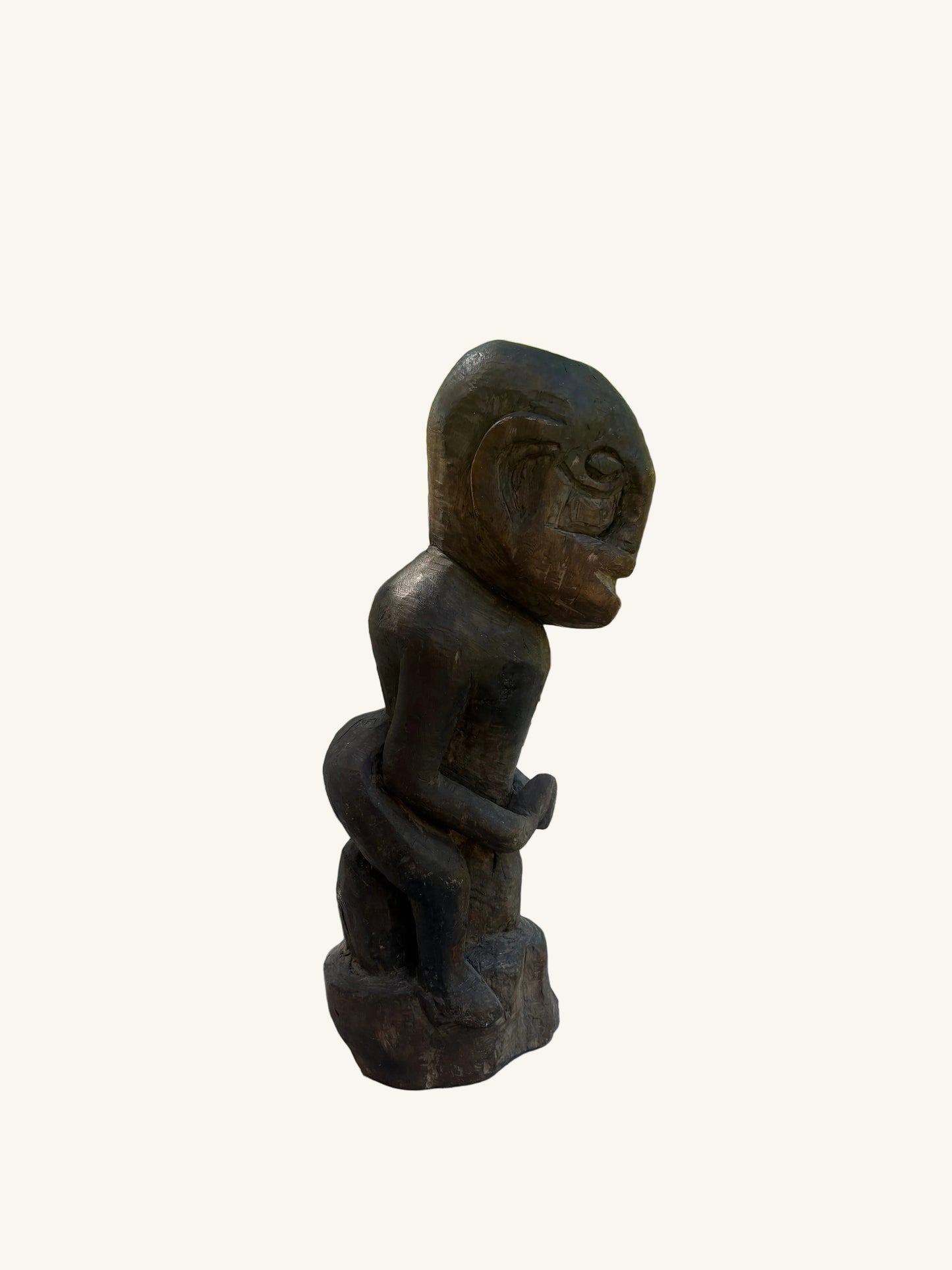 Wooden sculpture of a face on a stone surface with trees in the background