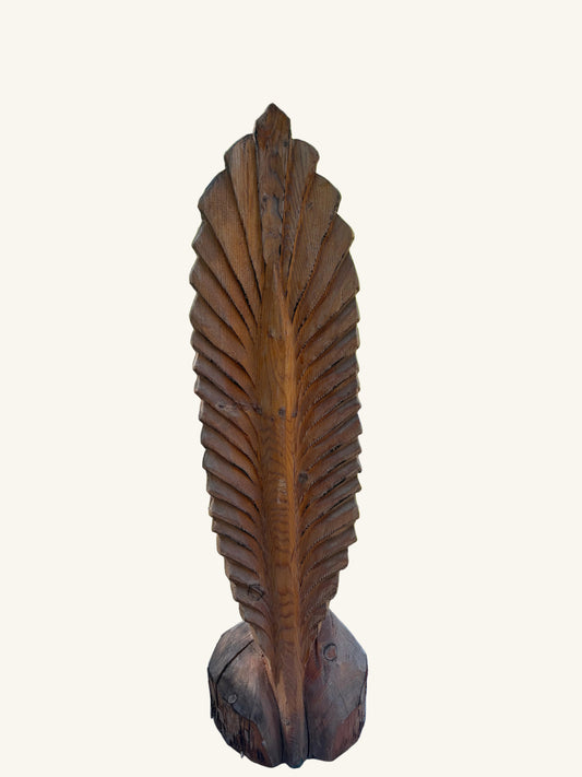 Wooden feather sculpture against white background. 